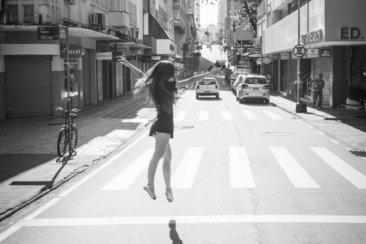 grayscale photo of woman walking on pedestrian lane