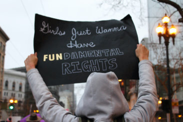 person in gray hooded jacket holding black sign