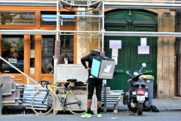 man in black jacket and black pants holding green and white book