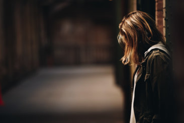 woman leaning against a wall in dim hallway