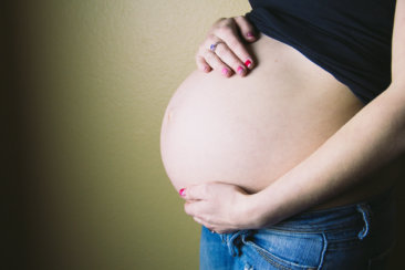 pregnant woman standing behind wall