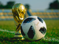 soccer ball beside trophy on soccer field