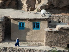 woman in blue dress sitting on gray concrete wall during daytime