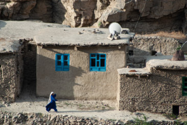 woman in blue dress sitting on gray concrete wall during daytime