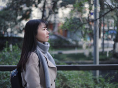 woman in gray scarf and coat standing near bridge