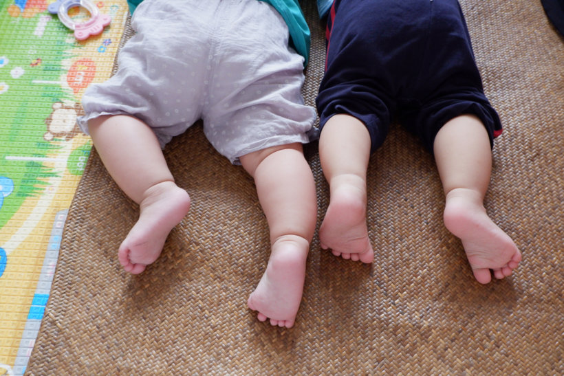 baby in white shirt and black pants lying on brown carpet