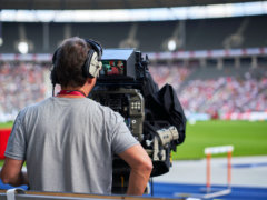 a man with headphones on sitting in front of a camera