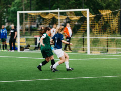 women playing soccer on green field during daytime