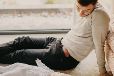 man in gray sweater lying on floor beside man in black shirt