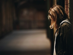 woman leaning against a wall in dim hallway