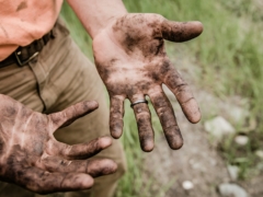 A man with his hands covered with mud