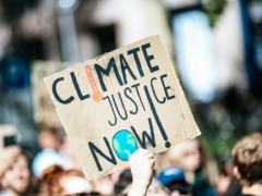 people gathered outside buildings holding Climate Justice Now signage