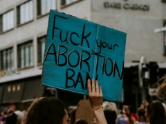 person holding fuck your abortion ban printed banner