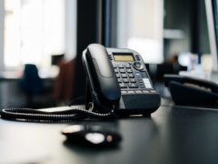 black ip desk phone on black wooden table